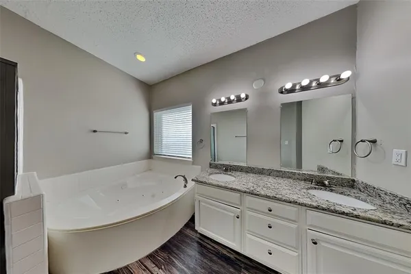 a bathroom with a granite countertop sink a large mirror and a bathtub