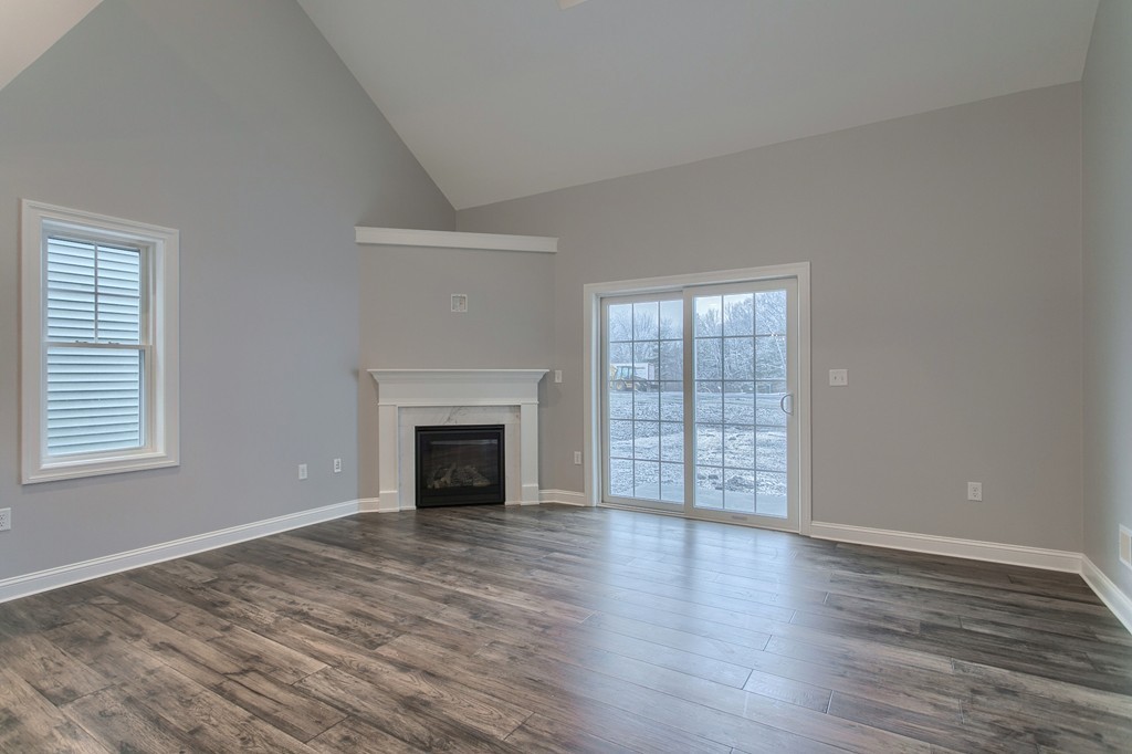 18 Jaclyn's Way, Unit 19 Billerica, MA 01821 - Photo 4 of 16 an empty room with wooden floor fireplace and windows