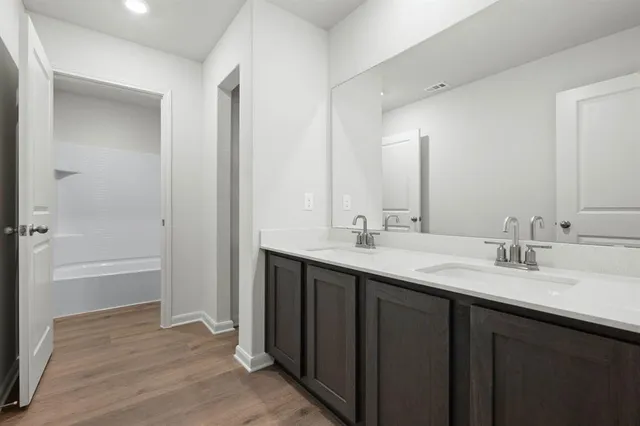 a bathroom with a sink double vanity granite tub shower and a mirror