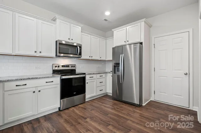 a kitchen with white cabinets and stainless steel appliances