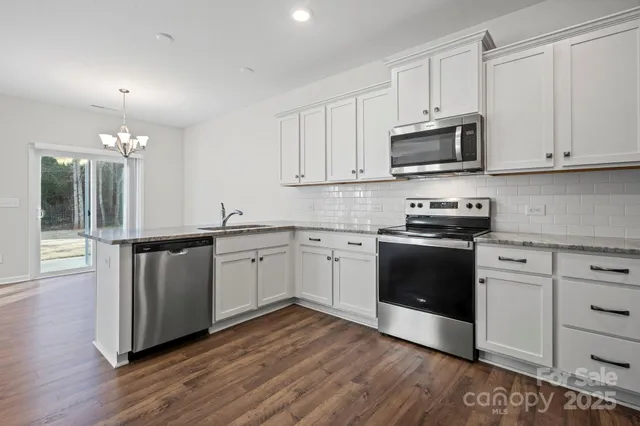 a kitchen with granite countertop white cabinets and stainless steel appliances
