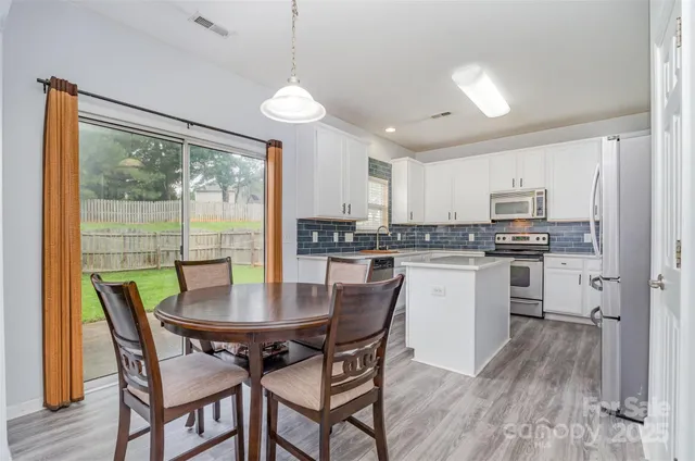 a kitchen with kitchen island a table and chairs in it