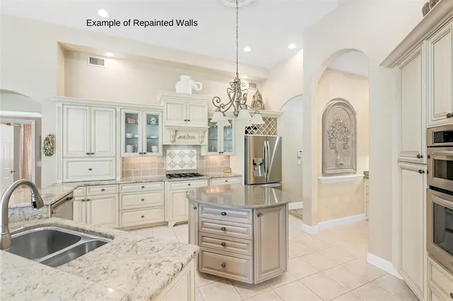 a kitchen with stainless steel appliances granite countertop a stove top oven a sink dishwasher and white cabinets with wooden floor