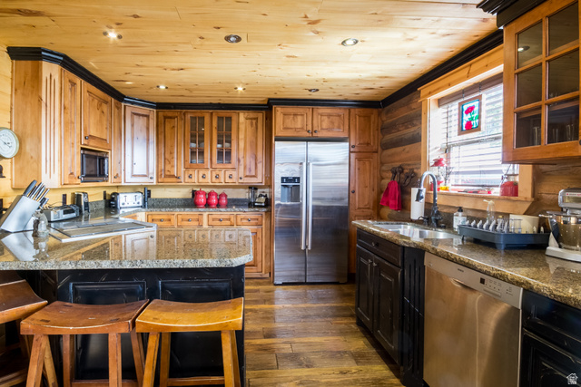 18906 North Canyon Road Whiterocks, UT 84085 - Photo 13 of 65 Kitchen with glass insert cabinets, appliances with stainless steel finishes, dark wood-style flooring, a breakfast bar, and brown cabinets