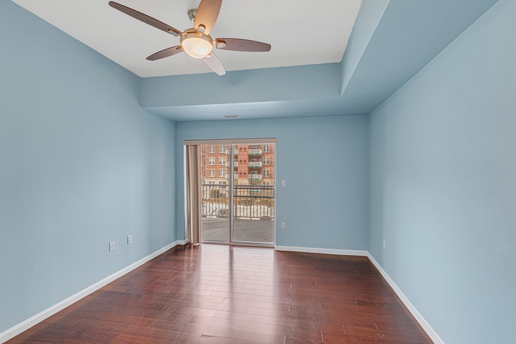 38 Village Road, Unit 305 Middleton, MA 01949 - Photo 13 of 25 an empty room with wooden floor chandelier fan and windows