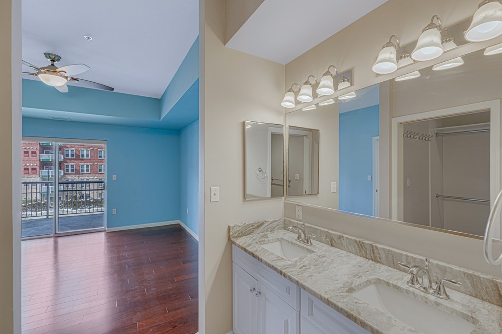 38 Village Road, Unit 305 Middleton, MA 01949 - Photo 16 of 25 a bathroom with a granite countertop sink a large mirror and a light fixture