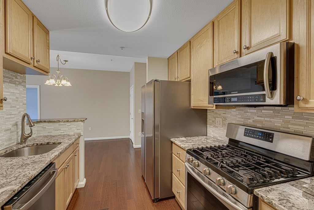 38 Village Road, Unit 305 Middleton, MA 01949 - Photo 6 of 25 a kitchen with stainless steel appliances granite countertop a stove a refrigerator and a sink