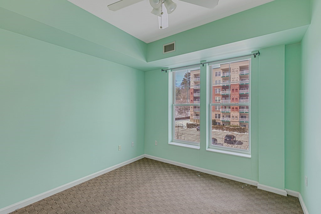38 Village Road, Unit 305 Middleton, MA 01949 - Photo 10 of 25 an empty room with windows and ceiling fan