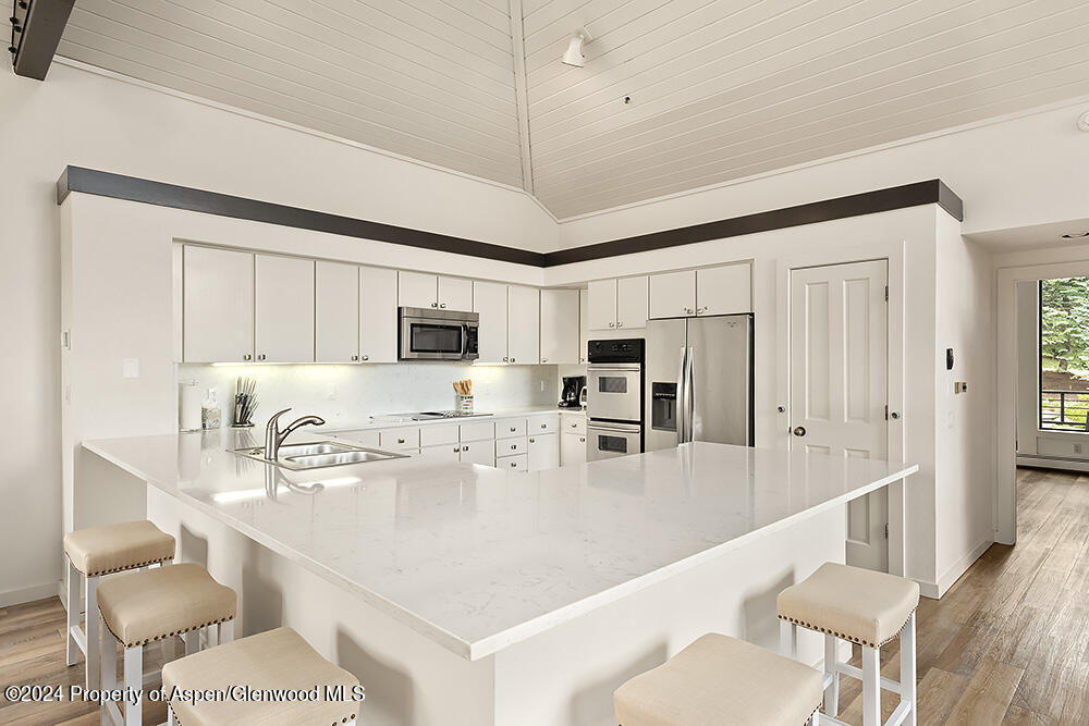 3904 Brush Creek Road, Unit 11 Snowmass Village, CO 81615 - Photo 11 of 25 a kitchen with stainless steel appliances granite countertop a sink a stove a refrigerator cabinets and chairs
