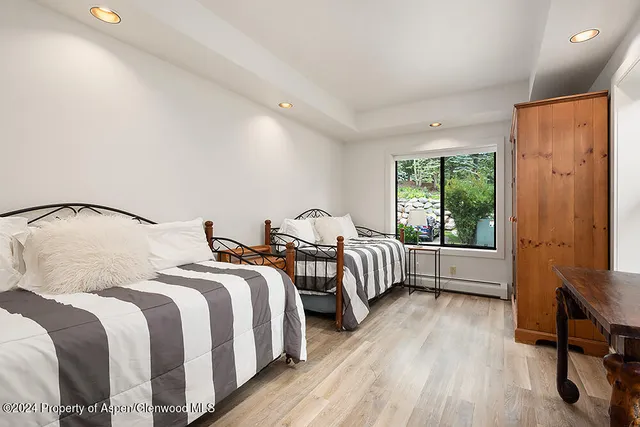 a bedroom with two beds and wooden floor