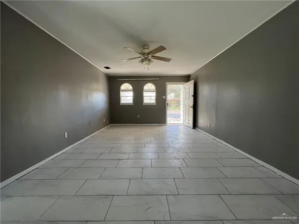 an empty room with windows and ceiling fan