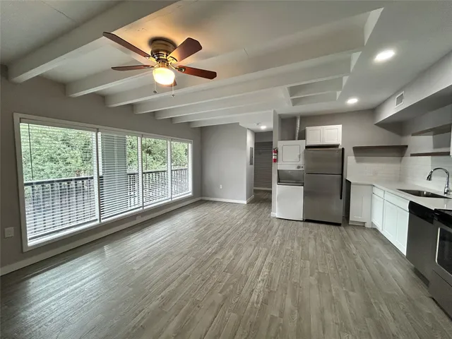a view of empty room with wooden floor and ceiling fan