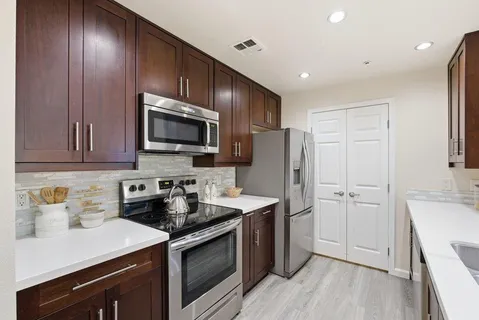 a kitchen with a sink a counter space and living room view
