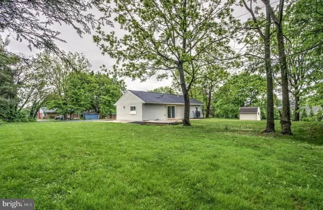 a view of a house with a big yard and large trees