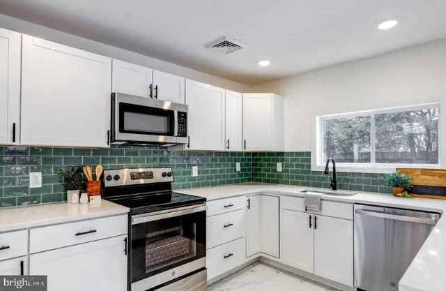 a kitchen with stainless steel appliances white cabinets and a sink