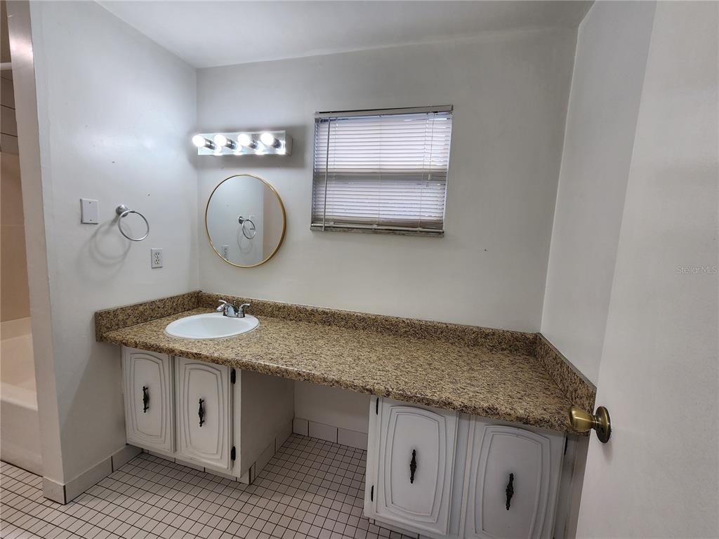 719 Southwest 75th Street, Unit 103 Gainesville, FL 32607 - Photo 14 of 28 a bathroom with a granite countertop sink and a mirror