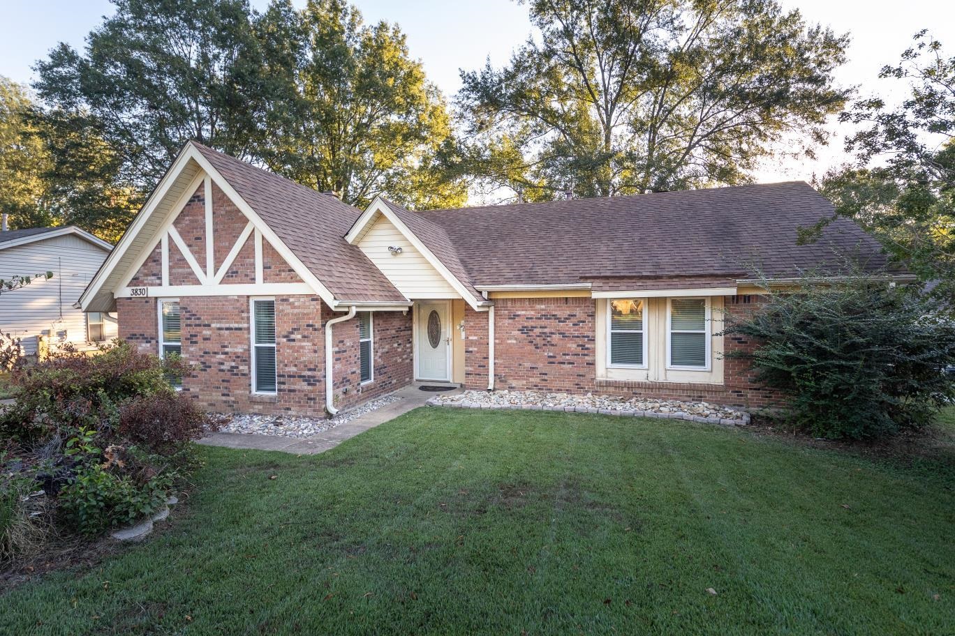 English style home with a front yard, roof with shingles, and brick siding