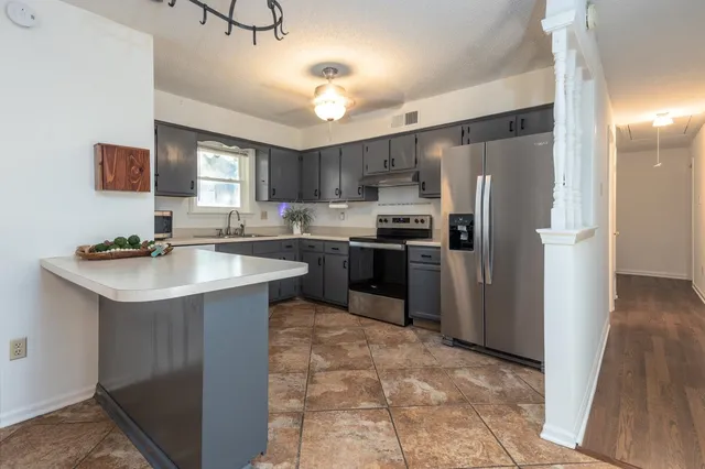 a kitchen with stainless steel appliances granite countertop a sink stove refrigerator and cabinets