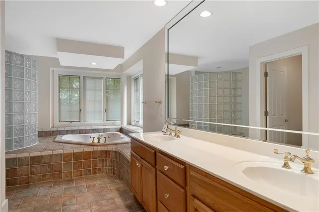 a bathroom with double vanity sinks double vanity tub shower and a mirror