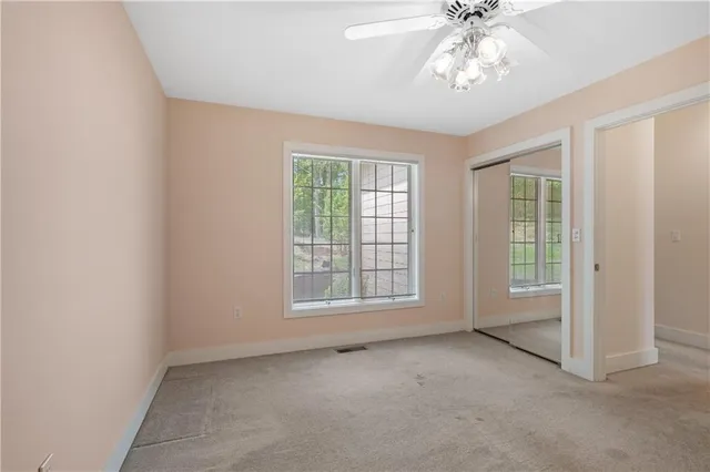 an empty room with chandelier fan and windows