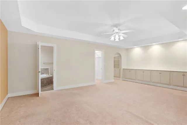 an empty room with chandelier fan and windows