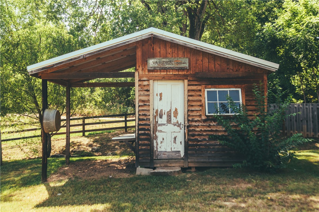 2026 Dry Creek Road St. Joe, AR 72675 - Photo 13 of 60 Wood-sided outbuilding featuring a covered porch, a single-pane window, and a wooden fence