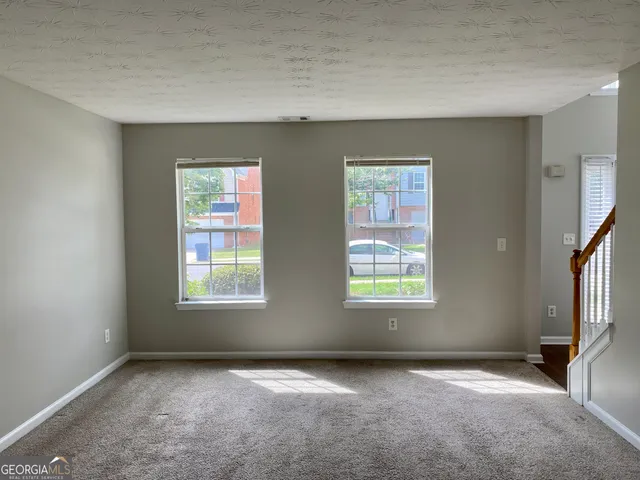 a view of an empty room with window and wooden floor