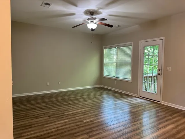 a view of an empty room with glass door and wooden floor