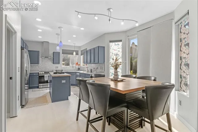 a dining room with stainless steel appliances kitchen island granite countertop a sink a stove a dining table and chairs