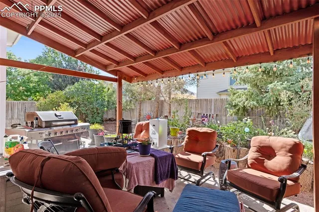 a view of a patio with table and chairs under an umbrella with large trees