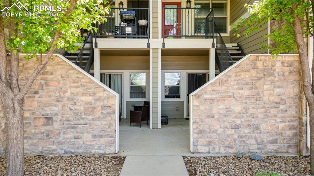 Lower-level patio area featuring concrete flooring and a stone-clad privacy wall