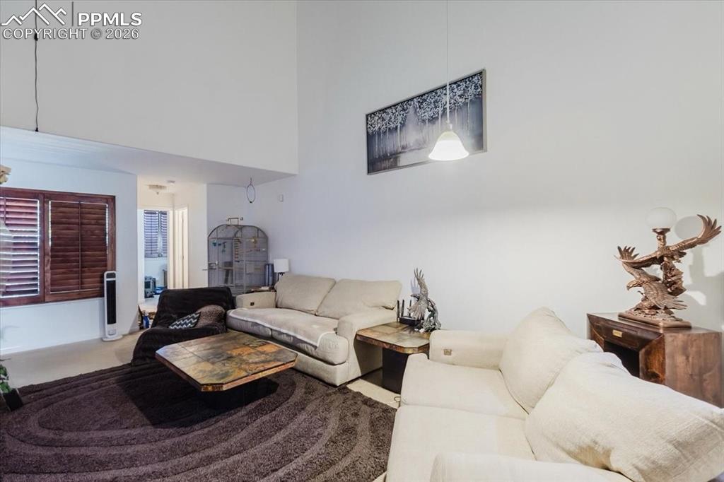5800 Tower Road, Unit 108 Denver, CO 80249 - Photo 13 of 35 High ceilings with a dedicated pendant light fixture, a window featuring wood plantation shutters, and light-toned wall finishes