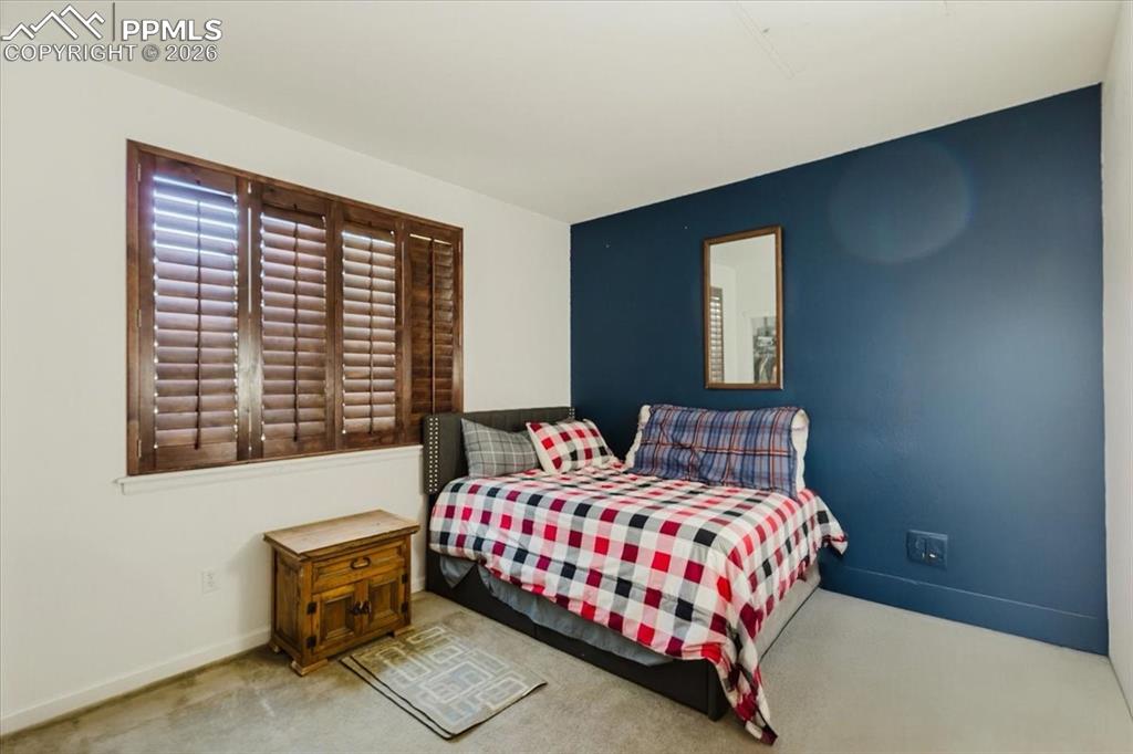 5800 Tower Road, Unit 108 Denver, CO 80249 - Photo 17 of 35 Interior room featuring wood plantation shutters, a dark accent wall, and neutral carpeting