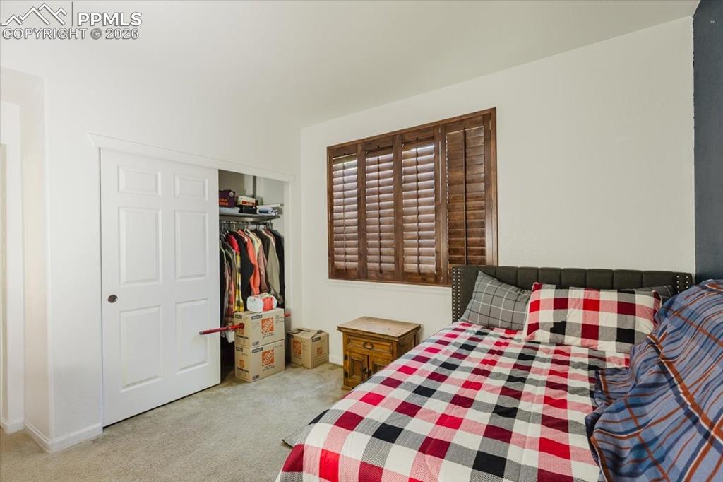 5800 Tower Road, Unit 108 Denver, CO 80249 - Photo 18 of 35 Room featuring a window with wood plantation shutters, light-toned carpeting, and a built-in closet with sliding panel doors