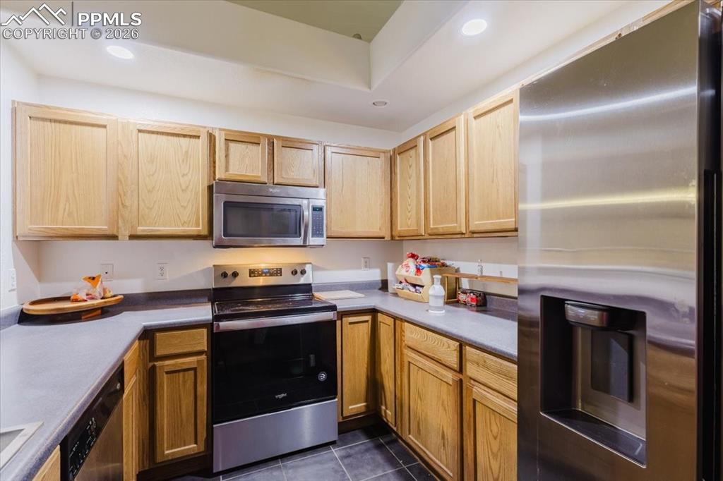 5800 Tower Road, Unit 108 Denver, CO 80249 - Photo 20 of 35 Kitchen featuring light wood cabinetry, stainless steel appliances including a refrigerator and microwave, a black electric range, and dark countertops