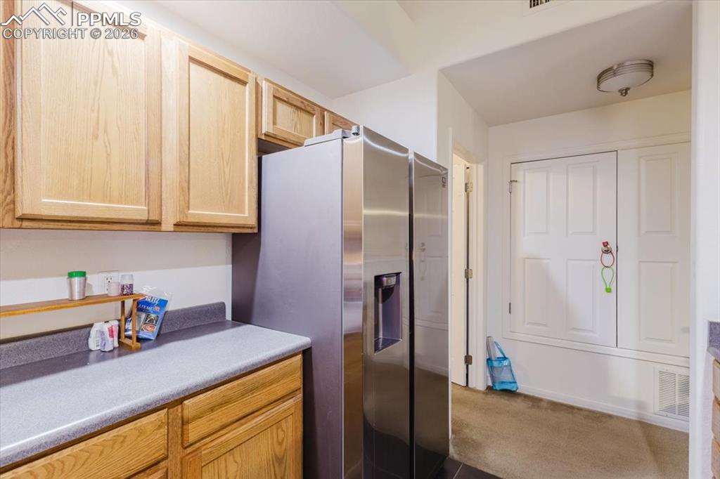5800 Tower Road, Unit 108 Denver, CO 80249 - Photo 22 of 35 Kitchen area featuring light wood cabinetry, a stainless steel refrigerator with a dispenser, and a dark countertop