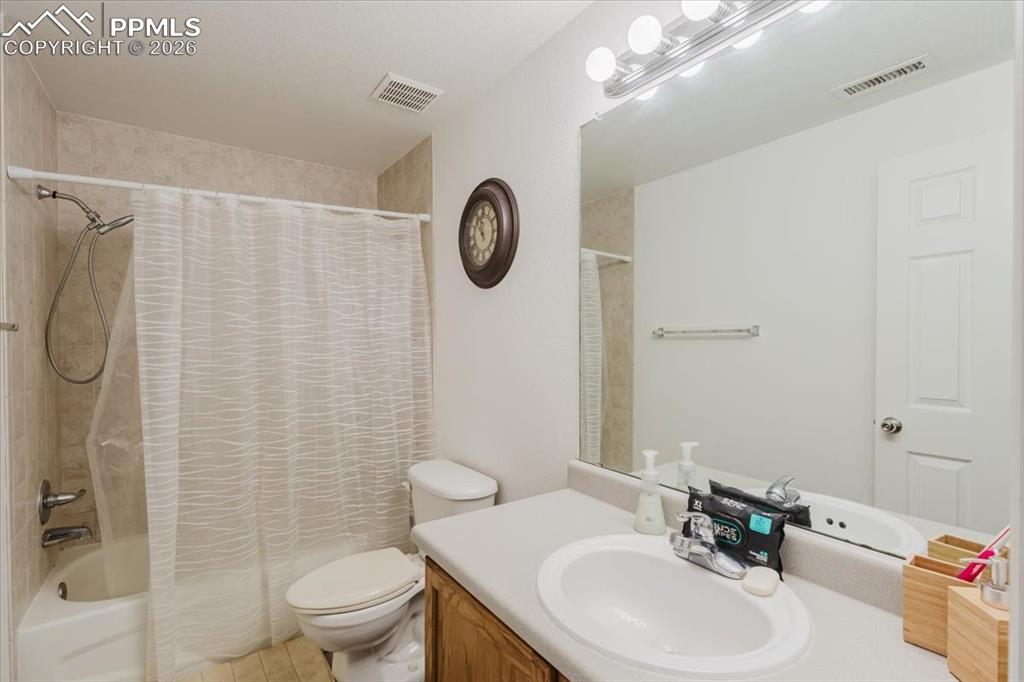 5800 Tower Road, Unit 108 Denver, CO 80249 - Photo 23 of 35 Full bathroom featuring a shower-over-tub combination with tiled surround, a vanity with a laminate countertop and integrated sink, a large wall-mounted mirror, and a globe light fixture