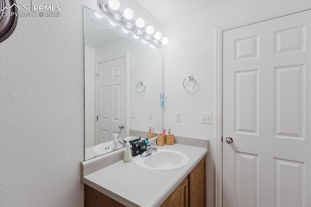 5800 Tower Road, Unit 108 Denver, CO 80249 - Photo 24 of 35 Vanity featuring a single basin sink, light-toned countertop, and wood-finish cabinetry