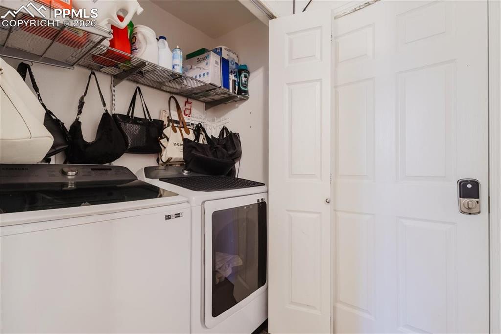 5800 Tower Road, Unit 108 Denver, CO 80249 - Photo 25 of 35 Dedicated laundry area featuring a white washing machine and dryer, overhead wire shelving, and paneled doors
