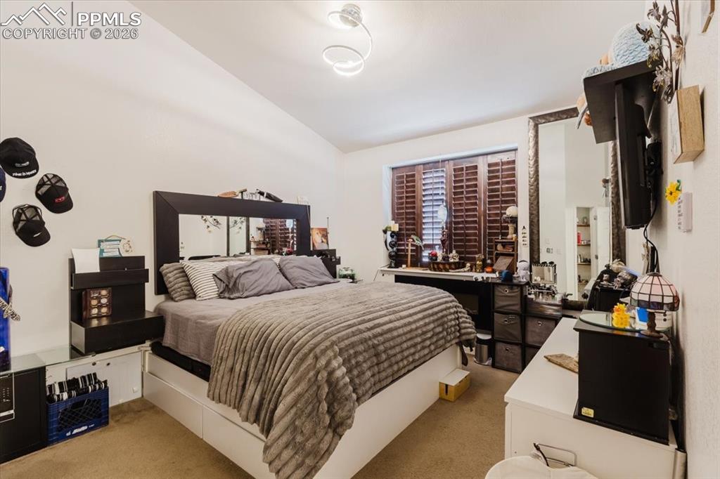 5800 Tower Road, Unit 108 Denver, CO 80249 - Photo 26 of 35 Bedroom featuring wood-finish plantation shutters, a mirrored bed frame, and wall-mounted light fixture