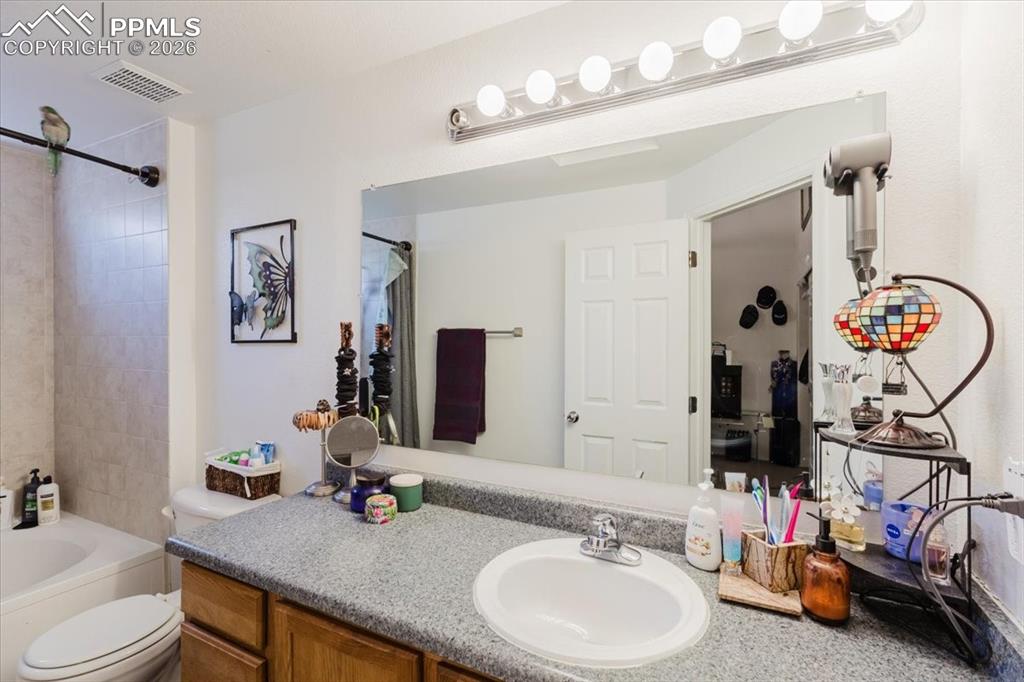 5800 Tower Road, Unit 108 Denver, CO 80249 - Photo 30 of 35 Bathroom vanity featuring an oval undermount sink, speckled countertop, and wood-finish cabinetry
