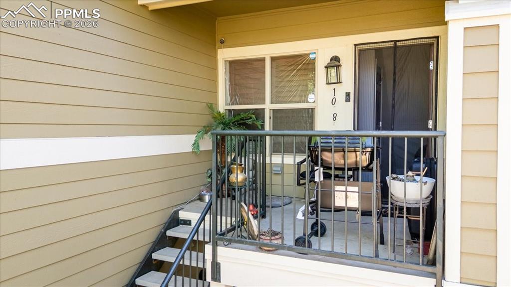 5800 Tower Road, Unit 108 Denver, CO 80249 - Photo 3 of 35 Private exterior patio featuring a privacy screen door, a wall-mounted light fixture, and horizontal siding