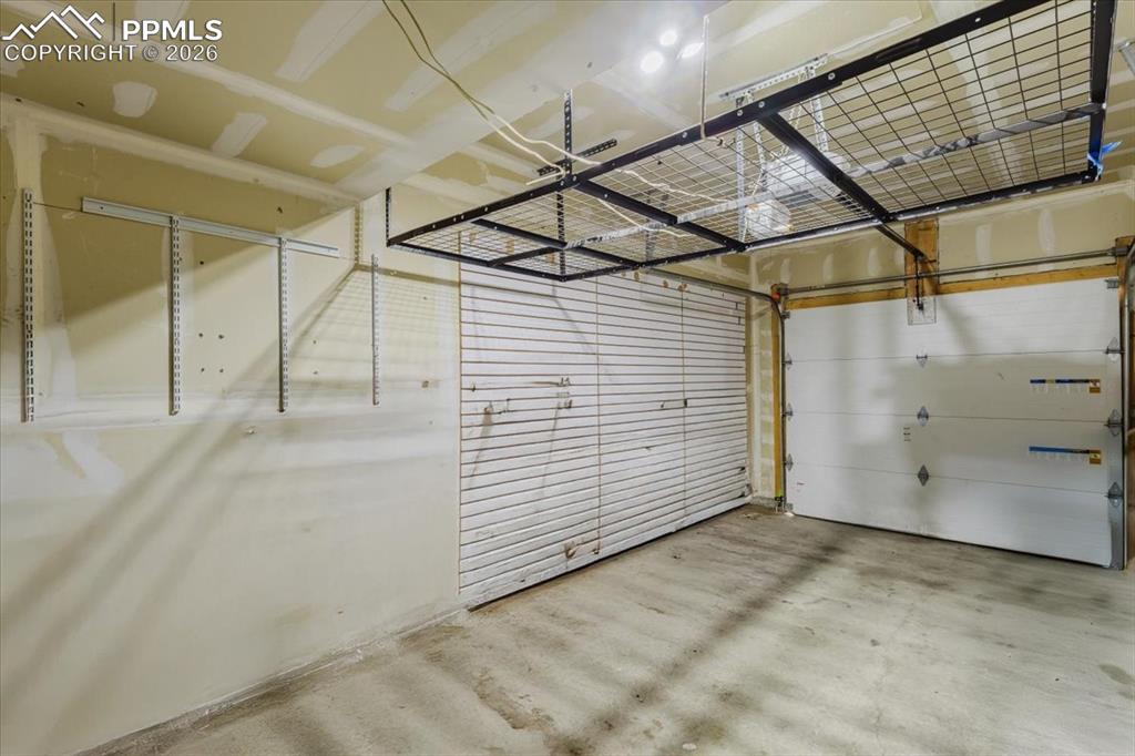 5800 Tower Road, Unit 108 Denver, CO 80249 - Photo 32 of 35 Spacious garage featuring concrete flooring, an overhead storage rack, and two garage doors