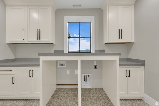 2828 Jojo Road Eagle Mountain, UT 84005 - Photo 34 of 63 Laundry room featuring a large window, patterned floor tile, extensive cabinetry with dark hardware, and a built-in counter for appliances
