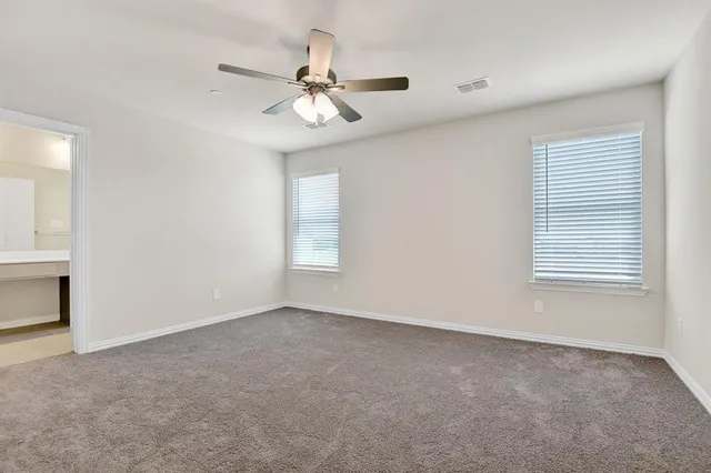 an empty room with windows and fan