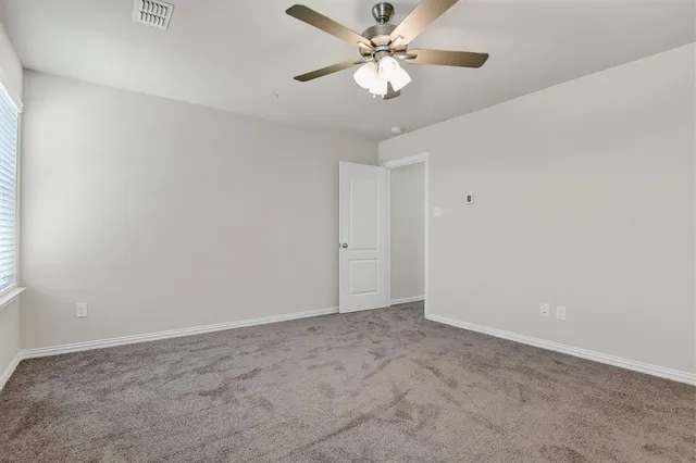 an empty room with a window and a fan
