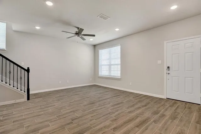 a view of empty room with wooden floor and fan