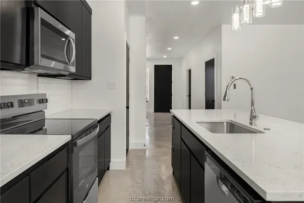 a kitchen with stainless steel appliances granite countertop a sink stove and microwave