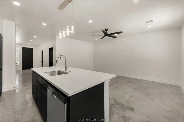 a view of a kitchen island a sink a refrigerator and a counter top space