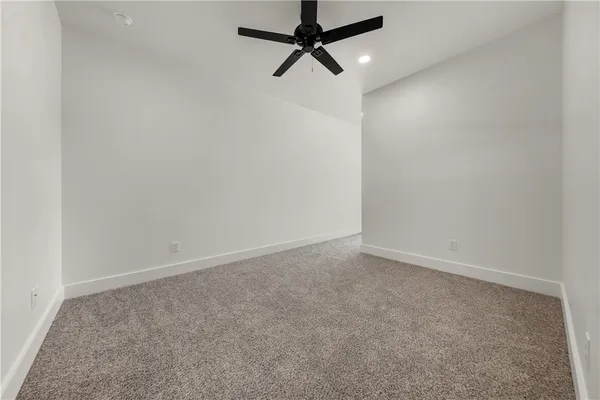 an empty room with a ceiling fan and carpet